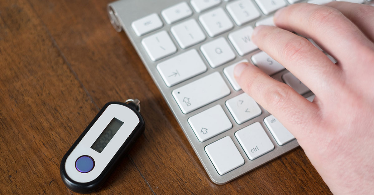 Photo of RSA code device on table next to keyboard while employee is typing