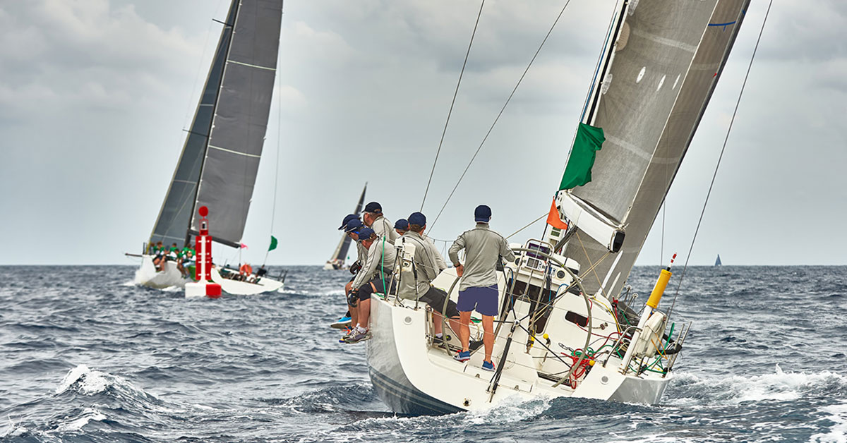 Photograph of a group of people sailing a boat in a regatta with lots of waves.